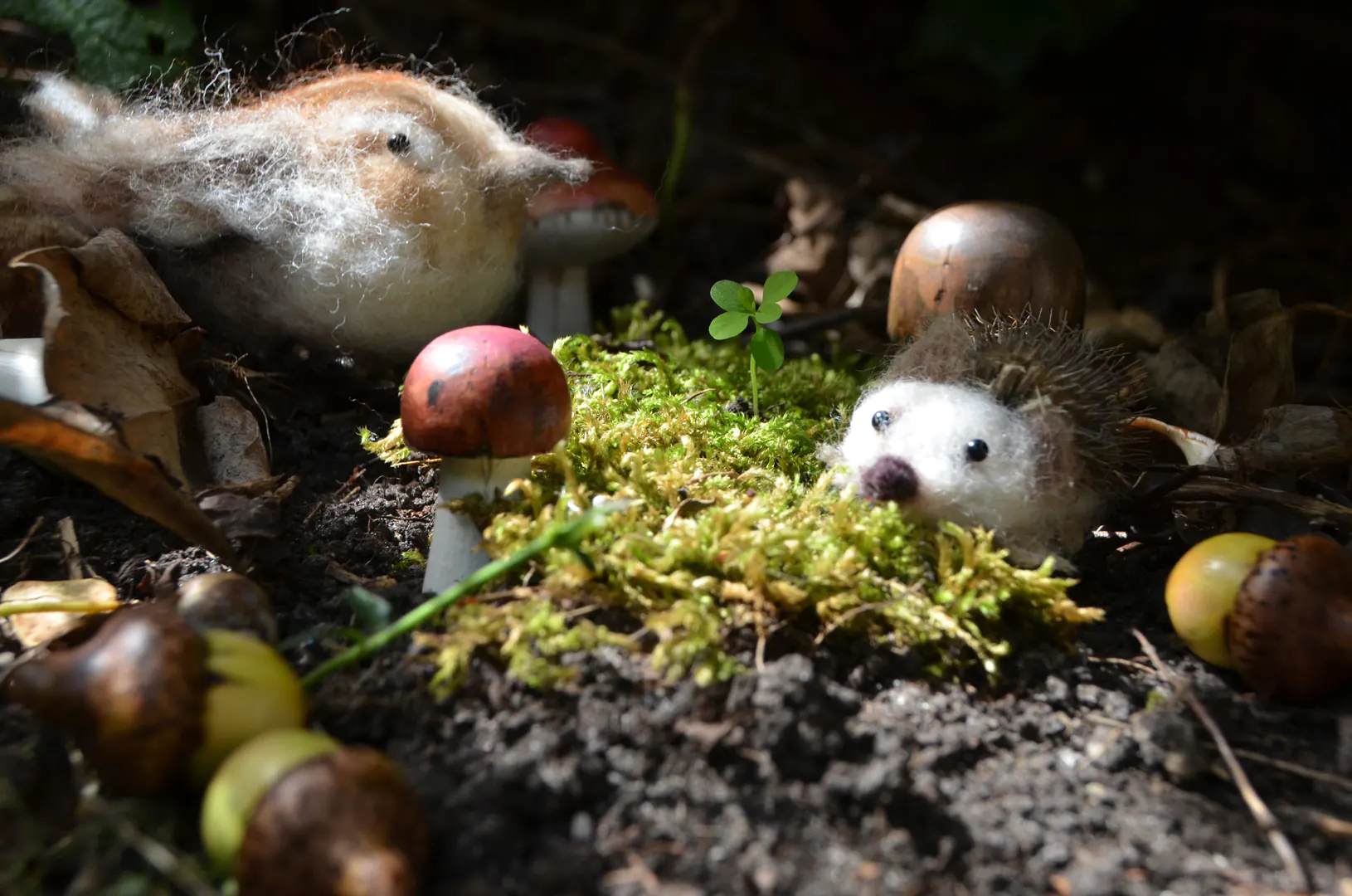 Handgevilte egel en vogel op ontdekking bij houten paddenstoelen en eikeltjes in het mos. Speelse Waldorf elementen als natuurlijke seizoensdecoratie voor de seizoenstafel.